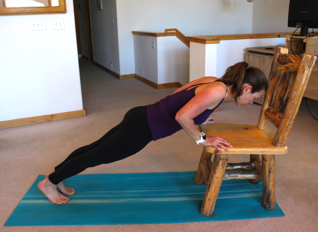 A woman demonstrating a push up progression for beginners.